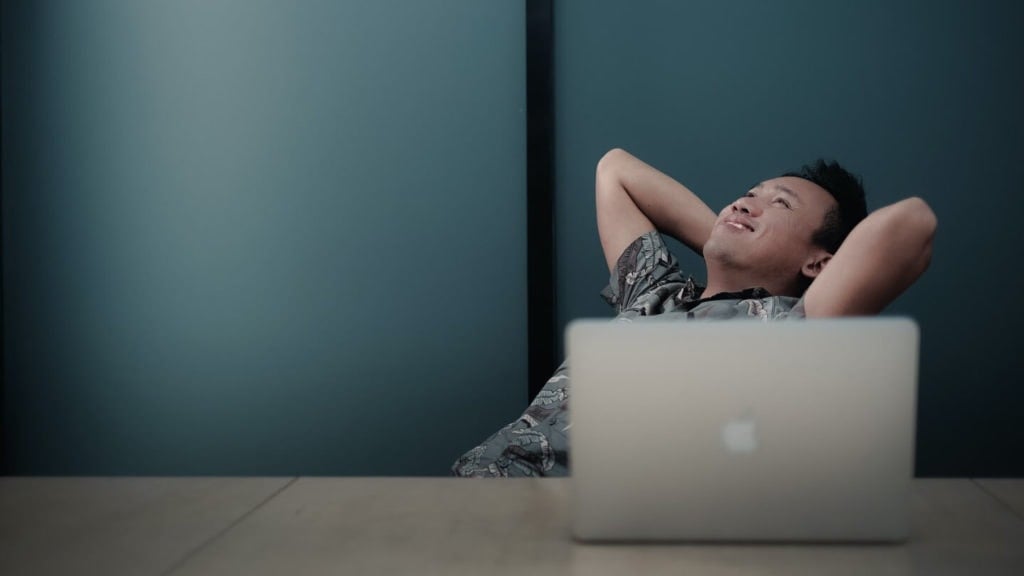 Employee leaning back and relaxing at desk with laptop, suggesting abuse of breaks and personal time during work hours