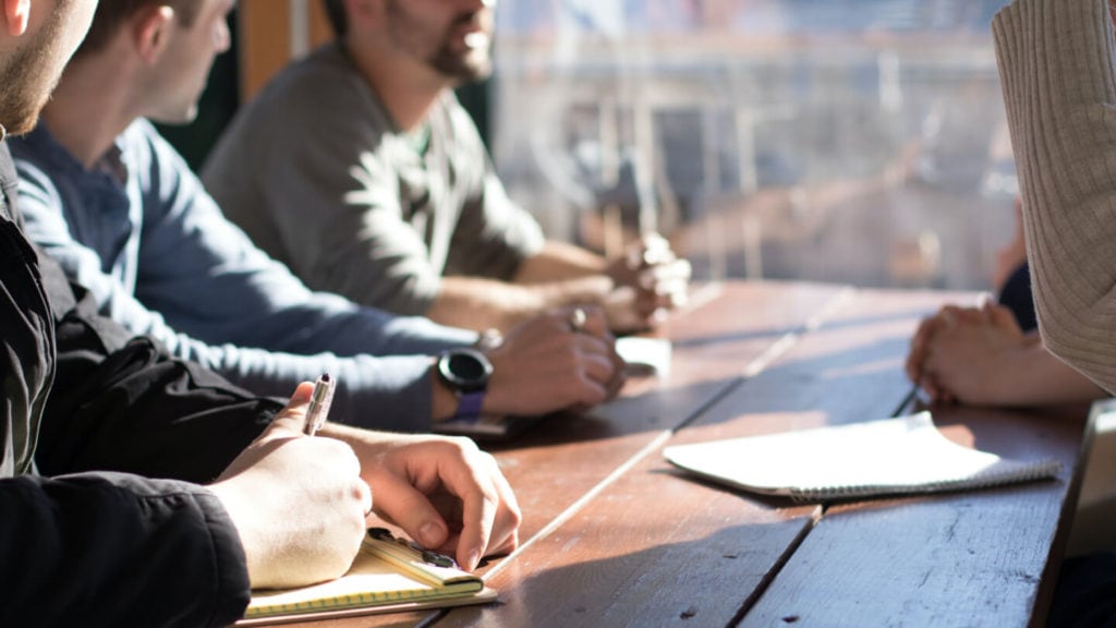 Close-up of a team meeting with people taking notes and discussing ideas, highlighting workplace communication
