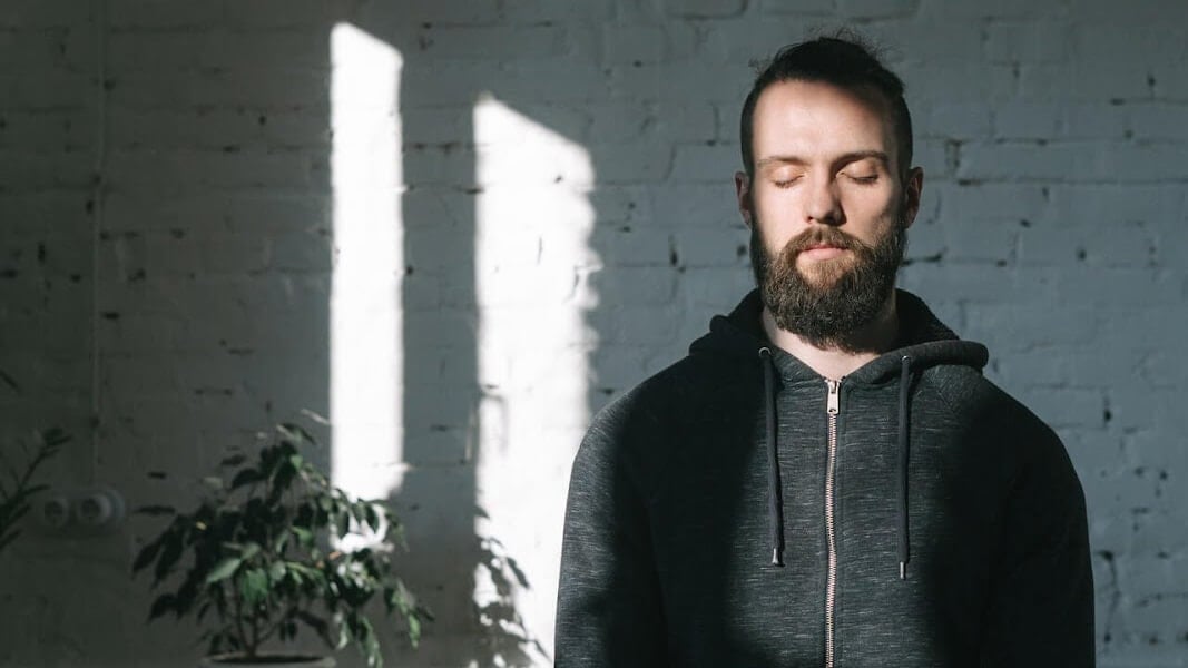 Man sitting and meditating to overcome anxiety | Hubstaff