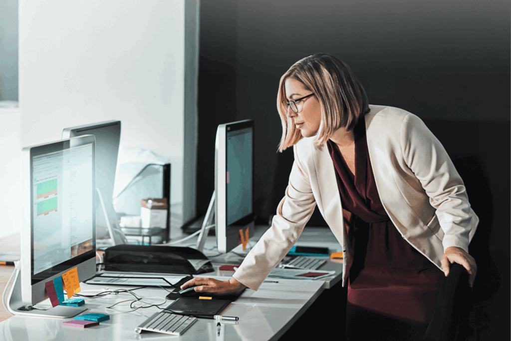 Image showing a woman reviewing exempt vs. nonexempt employee classifications at her desk in a modern office setting.