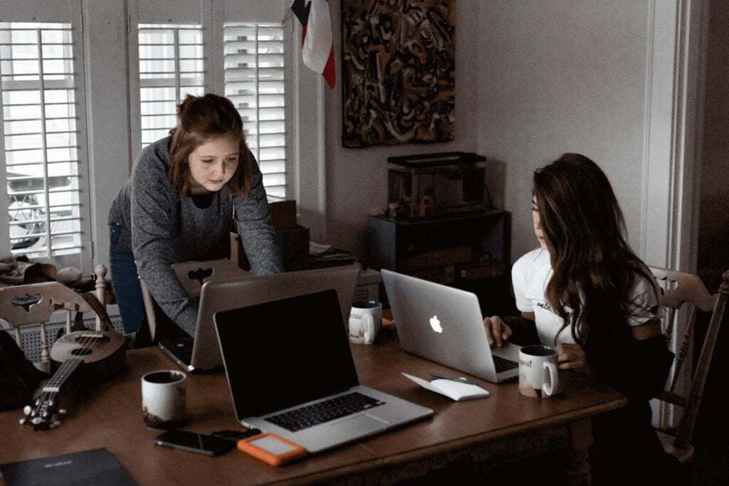Image showing two women working on laptops at a dining table in a home office.
